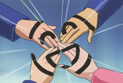 A screenshot from the anime Yu-Gi-Oh! Duel Monsters showing four hands together at the centre of a circle. A smiley face has been drawn with a black marker pen across the four hands.